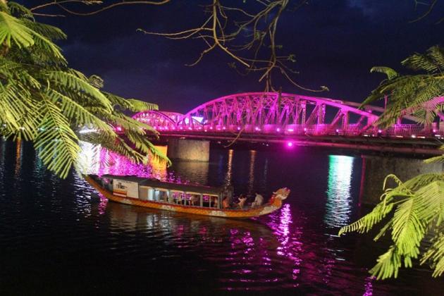 Khung cảnh sông Hương về đêm với ánh đèn phản chiếu trên mặt nước, tạo nên không gian thơ mộng cho trải nghiệm nghe Ca Huế khi đến Huế.